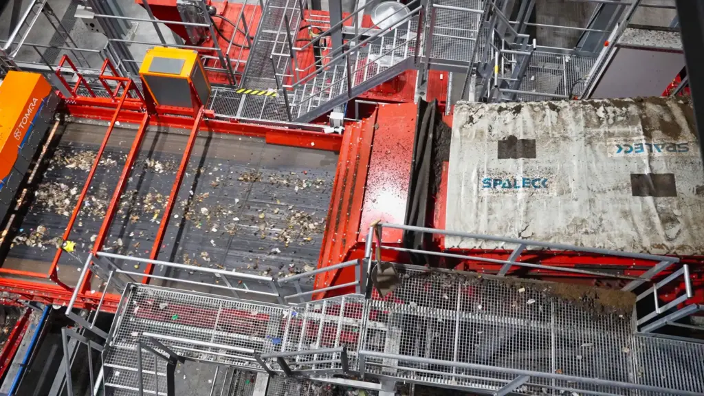 Tension-shaft screen (Flip-Flow screen) located upstream of a sorting machine at a household waste recycling plant. The SPALECK tensioned-shaft screen delivers precisely screened material. Screening out the fine fraction helps ensure that the subsequent sensor sorting (Tomra Machine) can function optimally.