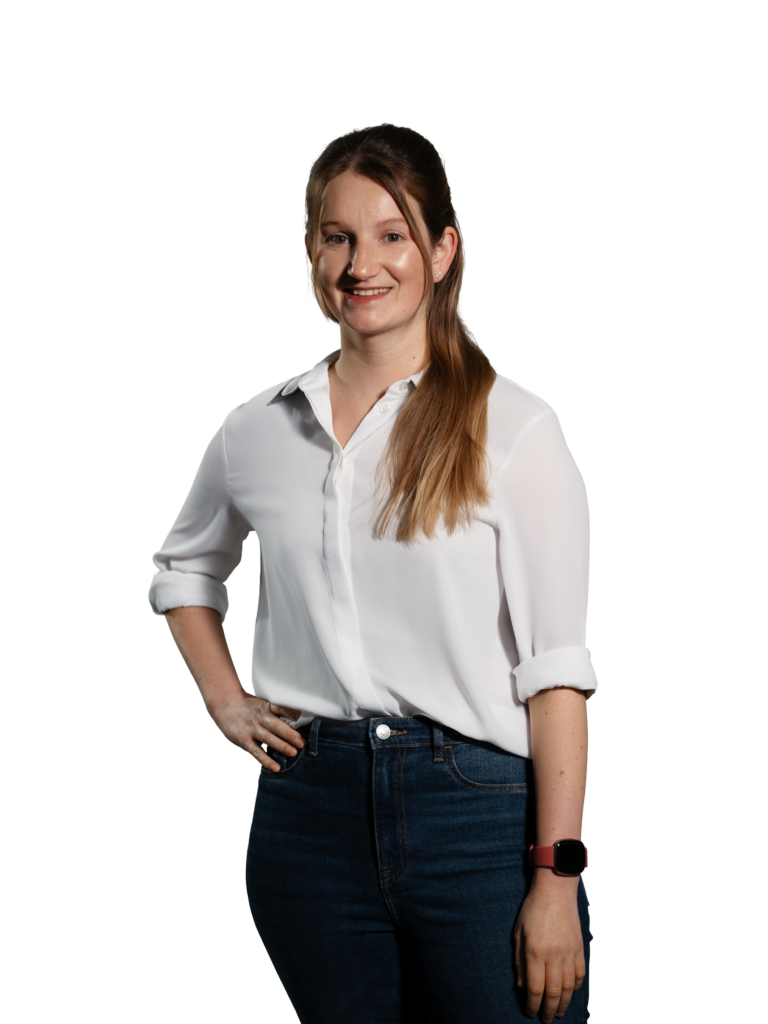 Frau in weißer Bluse und blauer Jeans mit langen Haaren, lächelnd.
